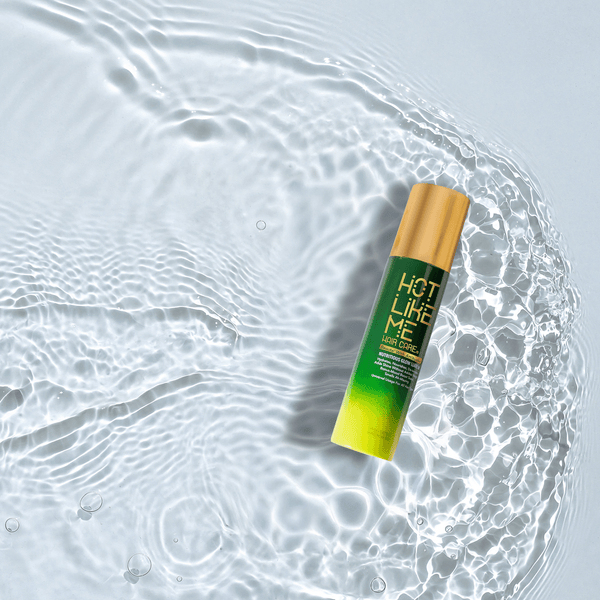 Bottle of Hot Like Me Hair Care Nutritious Glow Leave In Spray sitting in rippling water